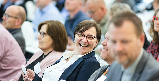 Mitbestimmen als Mitglied der PSD Bank Hannover eG Frau sitzt in einer Gruppe von Menschen